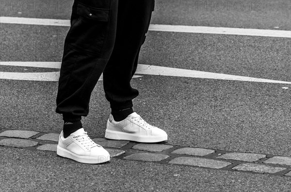 Man with white sports shoes standing on the marker of the former Berlin Wall