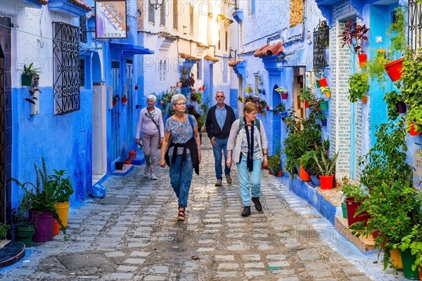 Western tourists walking in alley with blue houses in the medina