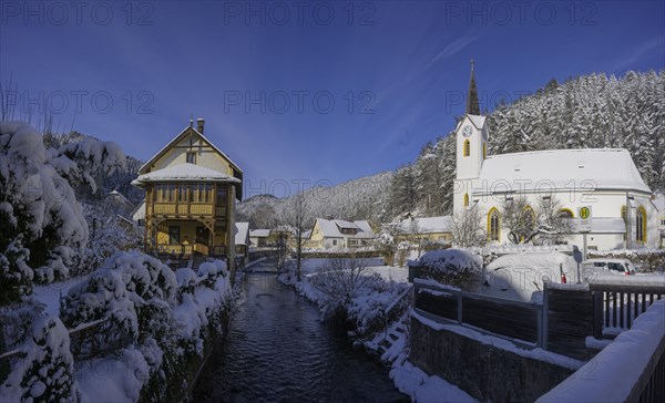 Old house with wooden balcony and parish church on the Piesting