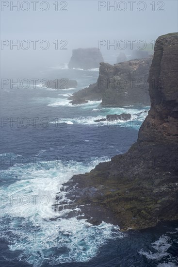 Sea stacks and sea cliffs in mist during stormy weather at Eshaness
