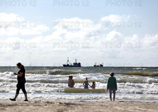 Family bathing with children on a North Sea fishing boat beach