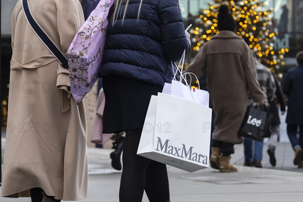 Christmas shopping at Outletcity Metzingen. Consumer tourists lug shopping bags. Factory outlet with around 80 shops of premium and luxury brands specialising in clothing