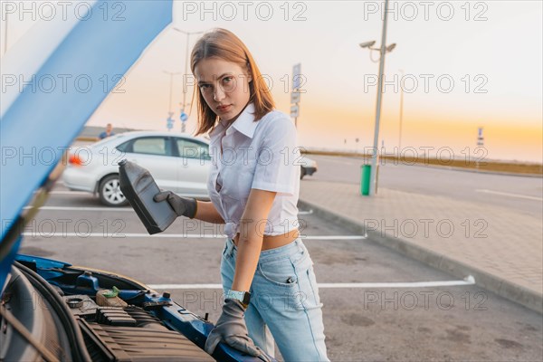 Young beautiful hot girl auto mechanic pours oil