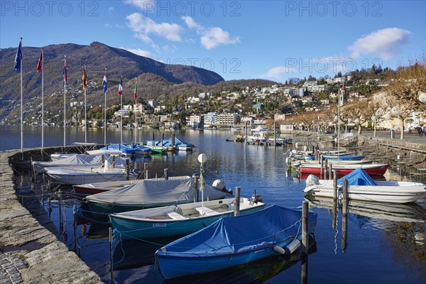 Motorboats and stone wall with flags in the harbour of Lake Maggiore in the bay of Ascona