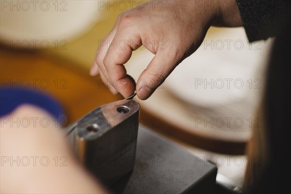 Unrecognizable luthier lute maker artisan hands in his workshop performing bend controller purfling strips process in iron tool for a new raw back and front plates of classic handmade violin in Cremona