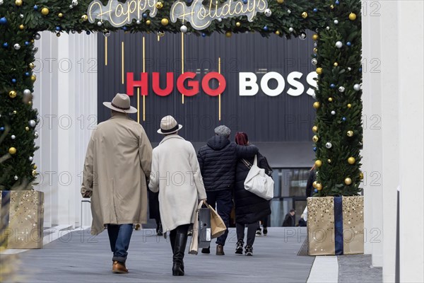 Christmas shopping at Outletcity Metzingen. Consumer tourists lug shopping bags. Factory outlet with around 80 shops of premium and luxury brands specialising in clothing