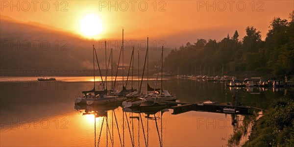 Sunrise over the Eder dam with dam wall and pleasure boats on the Edersee