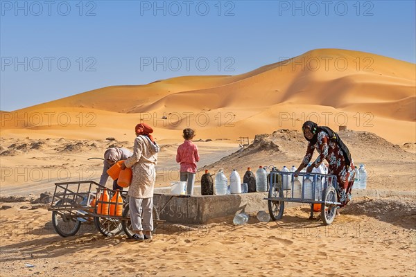 Moroccan Berber women collecting drinking water from well in Erg Chebbi in the Sahara Desert near Merzouga