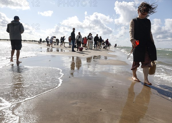 Tourists stand with one foot in the North Sea and one in the Baltic Sea in Grenen or Skagens Gren