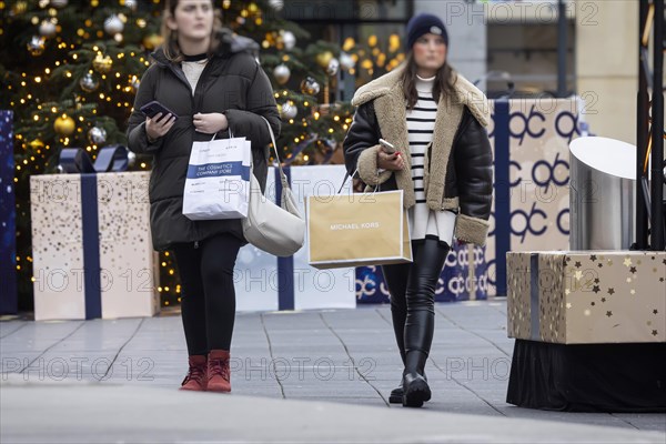 Christmas shopping at Outletcity Metzingen. Consumer tourists lug shopping bags. Factory outlet with around 80 shops of premium and luxury brands specialising in clothing