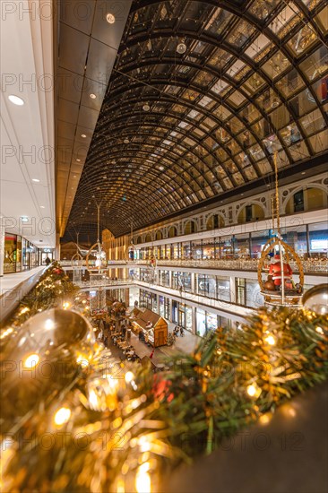 Interior of a shopping centre with festive Christmas lighting under a vaulted glass roof