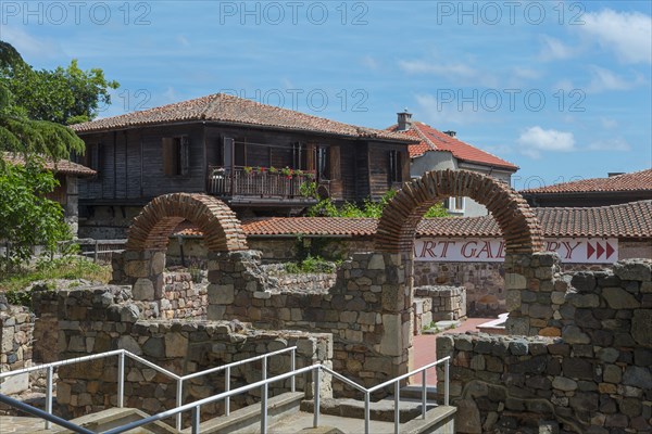 View of a traditional house behind old brick arches under a sunny sky