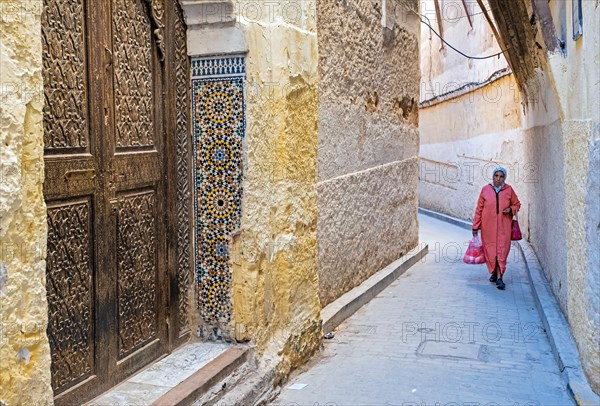 Beautiful carved wooden door and Muslim woman wearing djellaba