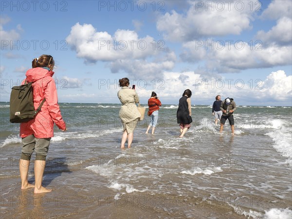 Tourists stand with one foot in the North Sea and one in the Baltic Sea in Grenen or Skagens Gren