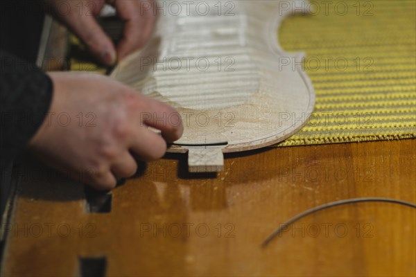Unrecognizable luthier lute maker artisan hands in his workshop putting fillet purfling strips into carved inlaid wood channel