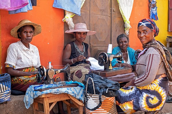 Seamstresses repairing clothes with antique sewing machines on street in the city Ambalavao