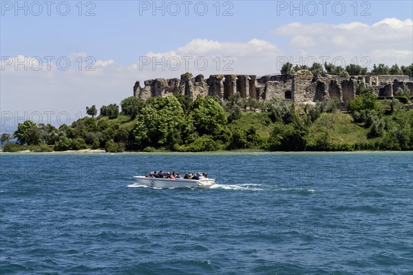 Boat with tourists in front of the Grottoes of Catullus