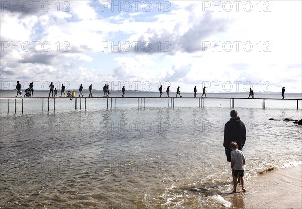 People walking on the infinite bridge . The bridge is a work of art built for Sculpture by the Sea