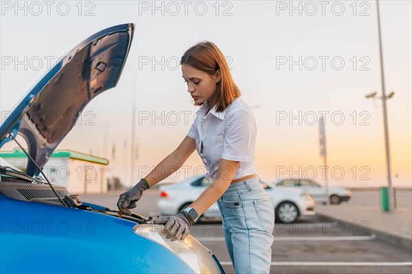 Young beautiful hot girl driver checks oil level