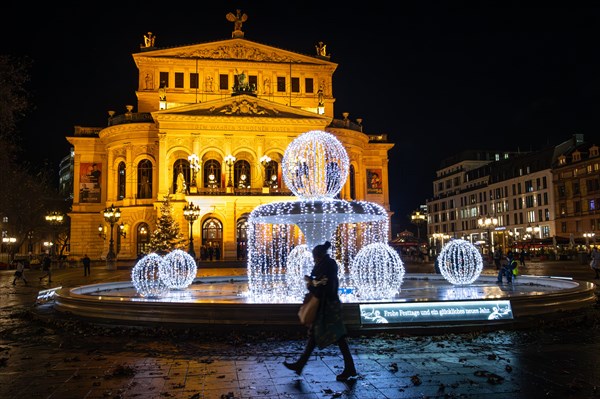 The silhouette of a passer-by is silhouetted against the glowing Christmas decorations on the Opernplatz at the Alte Oper in Frankfurt am Main