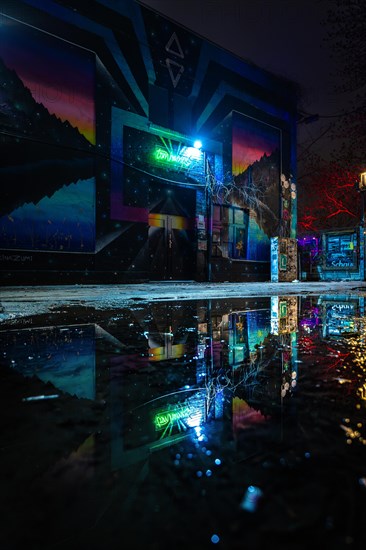 Urban corner with neon lights and reflections on a wet surface