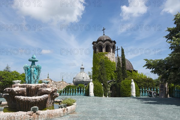 A chapel with religious statues and water basins surrounded by inviting greenery