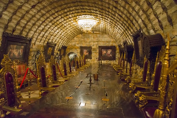 Historic interior with vaulted stone ceiling and ornate chairs under warm light