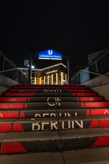 Entrance to a subway station at night with illuminated stairs with 'Berlin' written on them