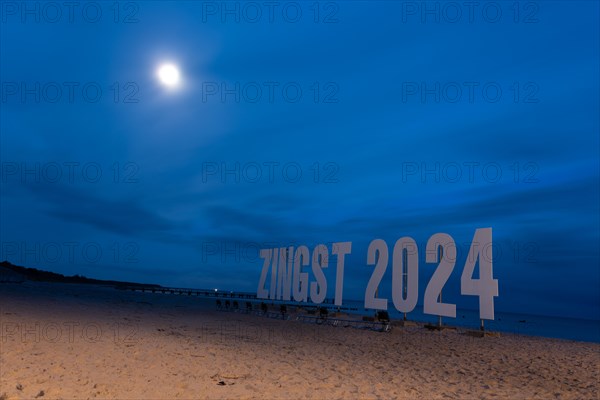 Moon shining over sign with lettering Zingst 2024