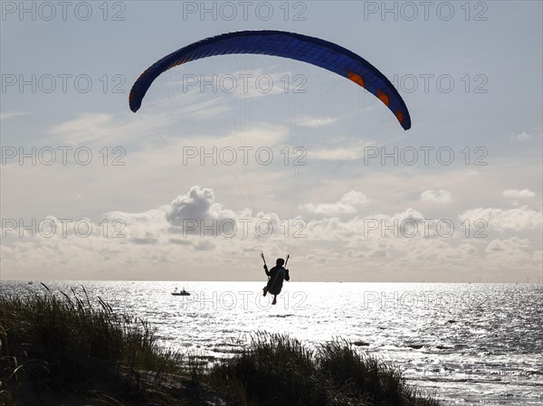 Paragliders flying over a beach at the North Sea