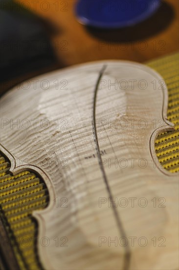 Front and back plates of new raw handmade classic violin on a workbench in violinmaker artisan workshop and purfling fillet made of evony and ivory or pear wood ready to be inserted in the carved all around the shape for aesthetic touch and prevent cracking