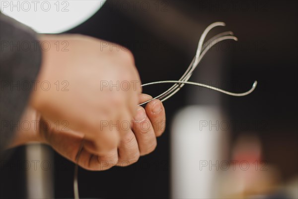 Violinmaker artisan hand in his workshop hold purfling fillet made of evony and ivory or pear wood ready to be inserted in the carved all around the shape for aesthetic touch and prevent cracking