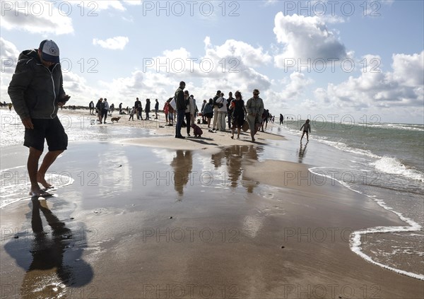 Tourists stand with one foot in the North Sea and one in the Baltic Sea in Grenen or Skagens Gren