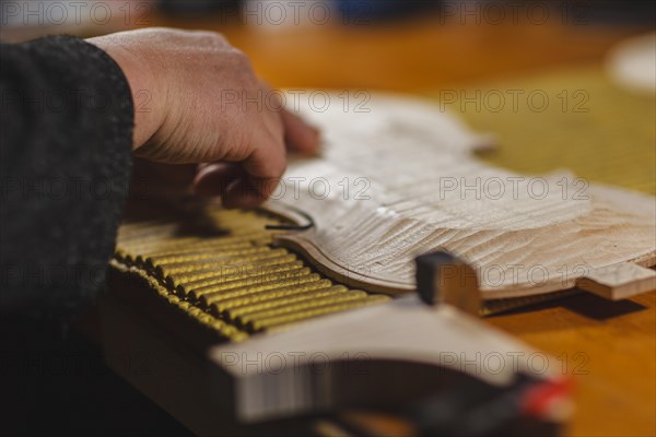 Unrecognizable luthier lute maker artisan hands in his workshop push and glue fillet purfling strips into carved inlaid wood channel