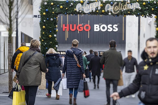 Christmas shopping at Outletcity Metzingen. Consumer tourists lug shopping bags. Factory outlet with around 80 shops of premium and luxury brands specialising in clothing