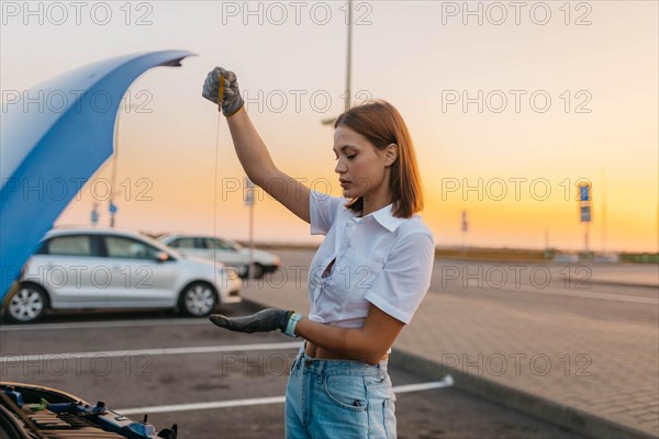 Young beautiful hot girl driver checks oil level