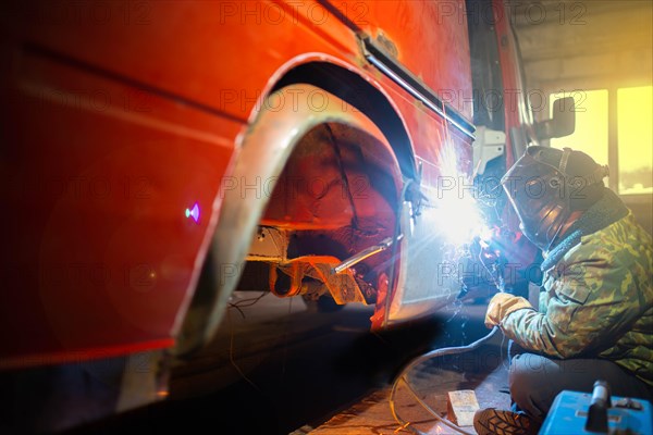 Welding work on car body repair in the garage. Truck repair