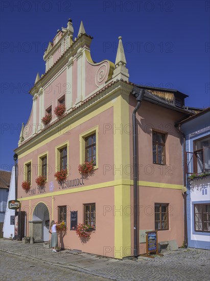 Woman watering flowers at a historic hotel building