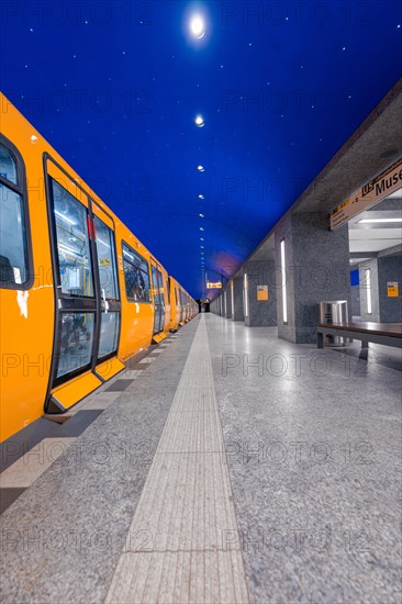 Yellow underground train on a platform at night with a clear starry sky