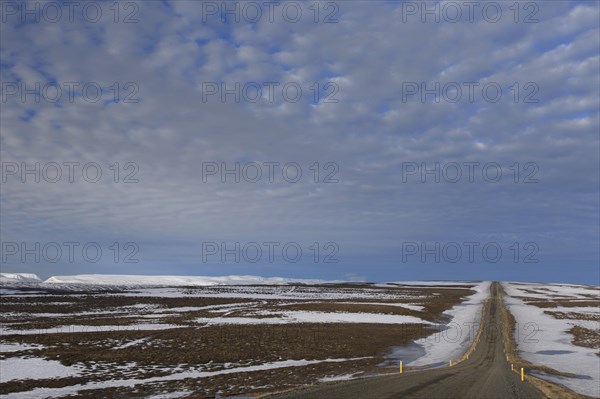 Road leading through the tundra towards the mountain range Lambafjoell