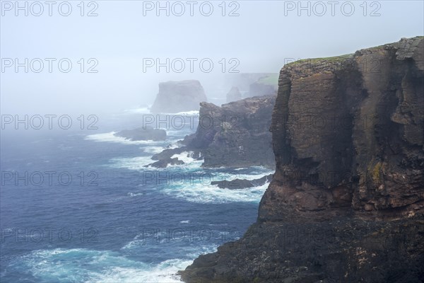 Sea stacks and sea cliffs in mist during stormy weather at Eshaness