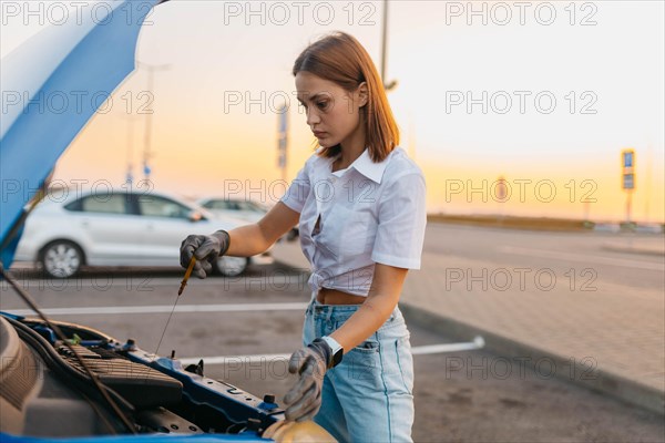 Young beautiful hot girl driver checks oil level