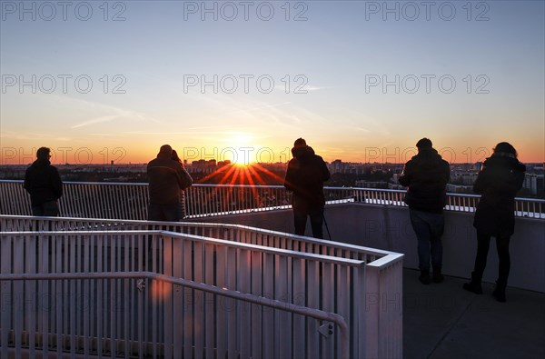 Visitors to a viewing platform enjoy the view over Berlin at sunset