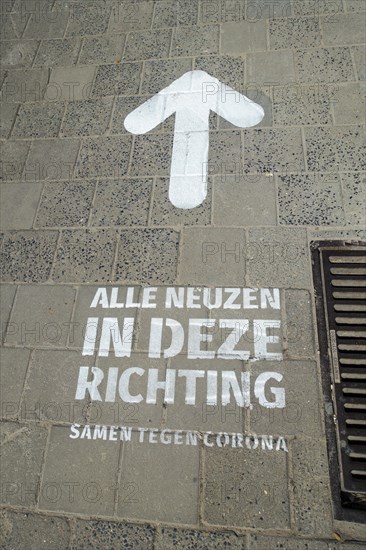 Arrow painted on pavement to indicate walking direction for shoppers in shopping street during 2020 COVID-19