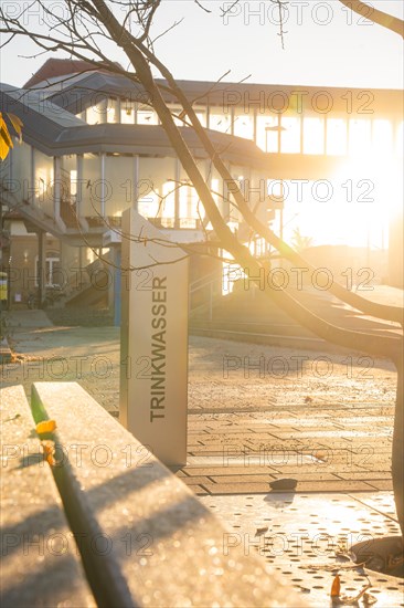 Autumn atmosphere with a drinking water column backlit by the sunset