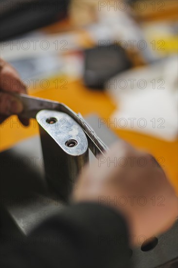 Unrecognizable luthier lute maker artisan hands in his workshop performing bend controller purfling strips process in iron tool for a new raw back and front plates of classic handmade violin in Cremona