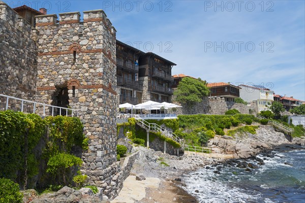 Traditional stone house on a rocky coastline with blue sky and sea in the background