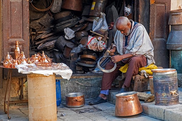 Moroccan coppersmith working in workshop on Place Seffarine