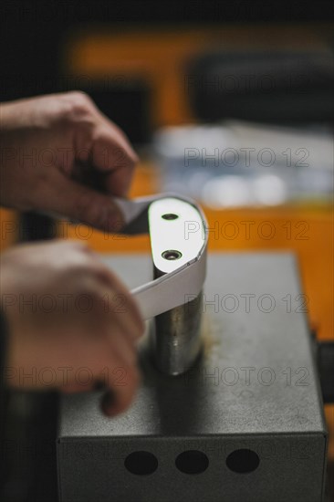 Unrecognizable luthier lute maker artisan both hands performing bend controller purfling strips process in iron tool for a new raw back and front plates of classic handmade violin in his workshop in Cremona