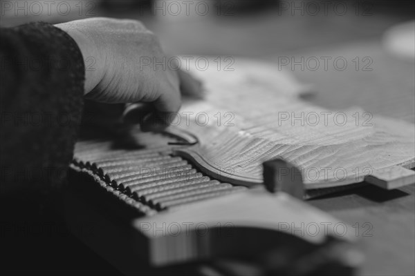 Violinmaker artisan hand in his workshop hold purfling fillet made of evony and ivory or pear wood ready to be inserted in the carved all around the shape for aesthetic touch and prevent cracking